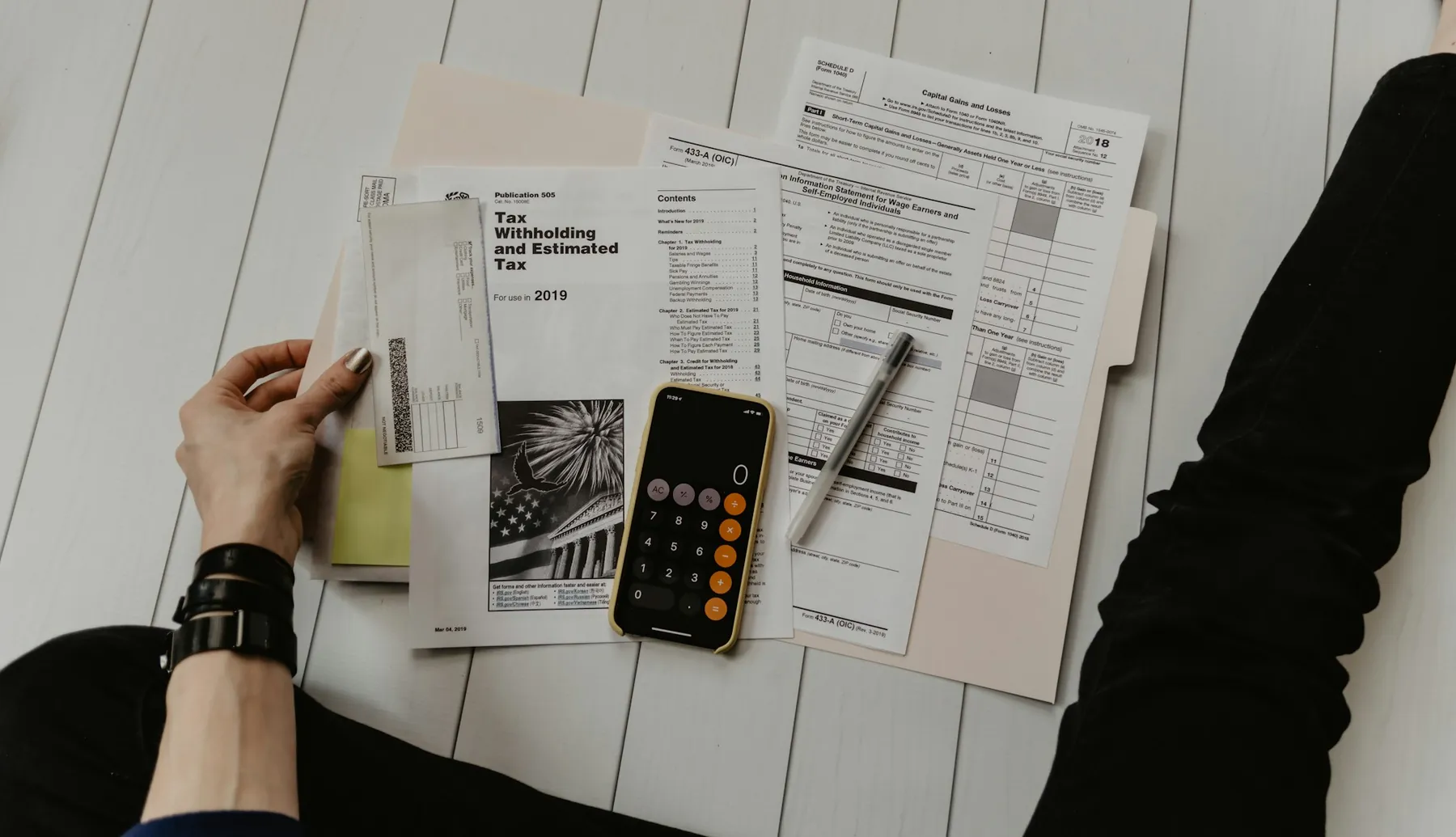 Hands sorting through tax paperwork and a calculator on a desk